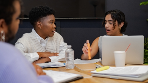 A trans person and a trans man discussing something in a meeting.jpg